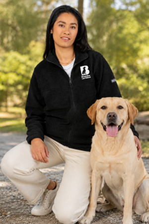 Brookline Lab Rescue embroidered Columbia fleece jacket worn outdoors with a yellow Labrador, featuring the embroidered Brookline Lab Rescue logo on the left chest.