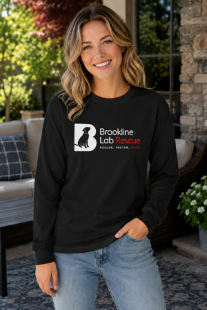 Woman wearing a black Brookline Lab Rescue Gildan 2400 long sleeve T-shirt featuring the official Brookline Lab Rescue logo while standing on a sunny outdoor patio.