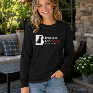 Woman wearing a black Brookline Lab Rescue Gildan 2400 long sleeve T-shirt featuring the official Brookline Lab Rescue logo while standing on a sunny outdoor patio.
