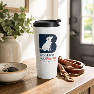 Brookline Lab Rescue 15 oz stainless steel travel mug displayed on a wooden entryway table beside a leather dog leash, house keys, and a ceramic bowl, with warm natural light streaming through the front door.